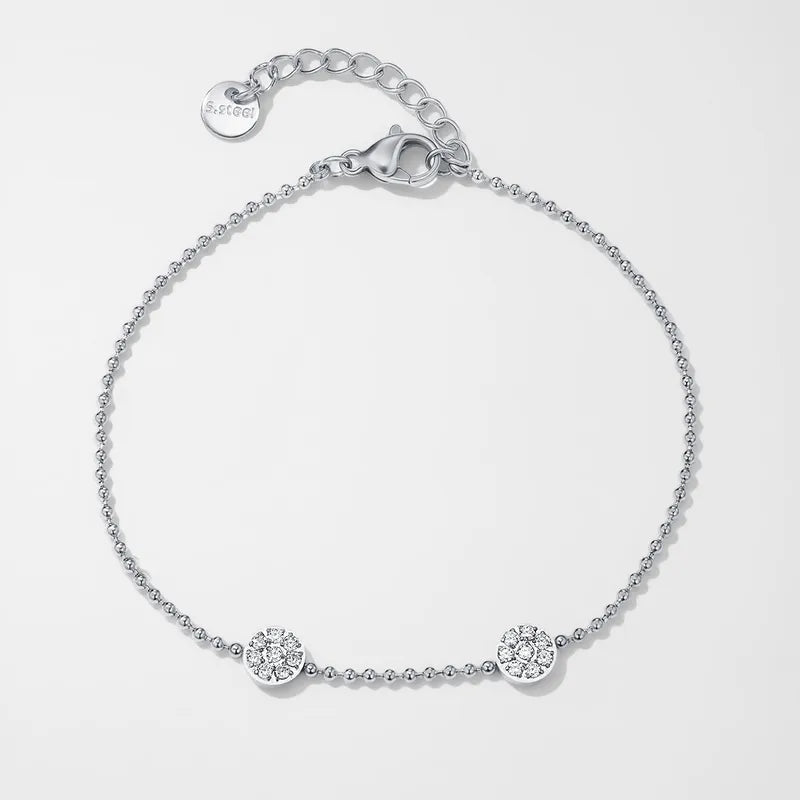 K23 - Pulsera delgada con dos dijes redondos con circonias. Color plateado. Acero inoxidable.