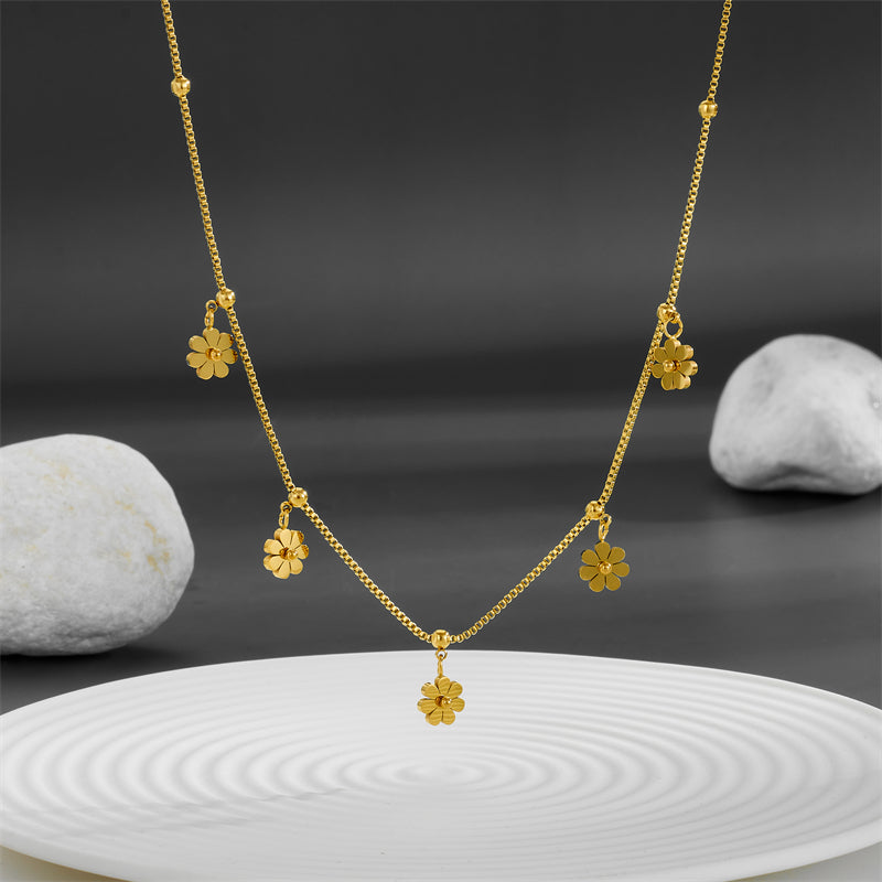 Cadena delgada con varios dijes de florecita. Color dorado. Acero inoxidable.