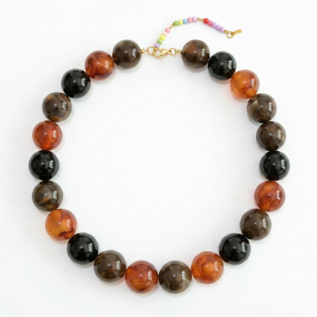 A06 - Collar bolas tonos negros, café, naranja. Resina.