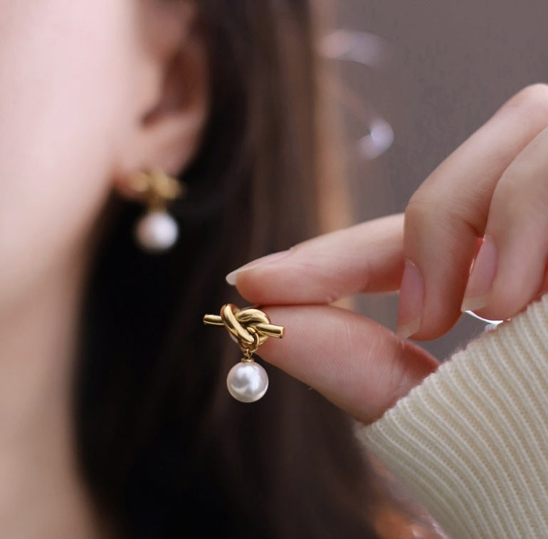 A22 - Arete nudo con perla. Color dorado. Acero inoxidable.