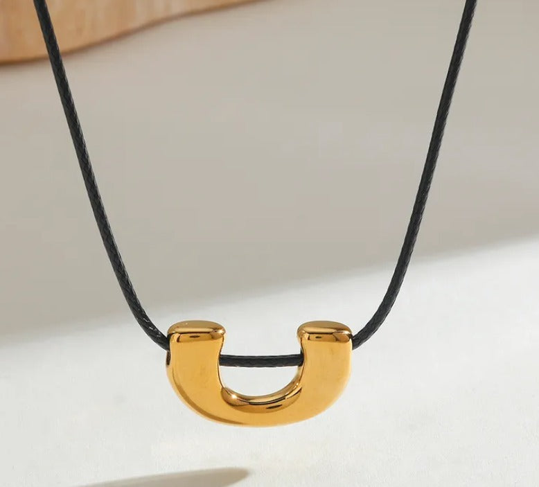 D07 - Collar ajustable con dije. Color negro y dije dorado. Acero inoxidable.