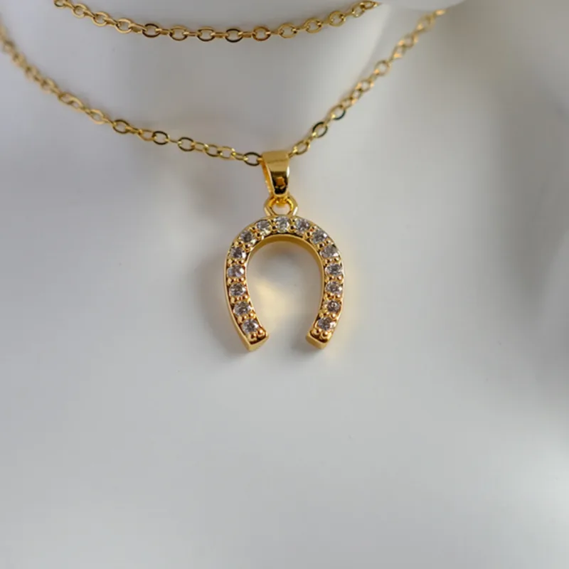 D09 - Collar dije herradura con circonias. Color dorado. Acero inoxidable.