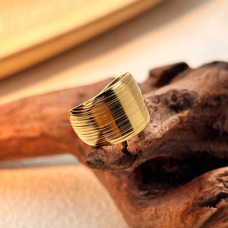 E06 - Anillo grueso con textura, ajustable. Color dorado. Acero inoxidable.