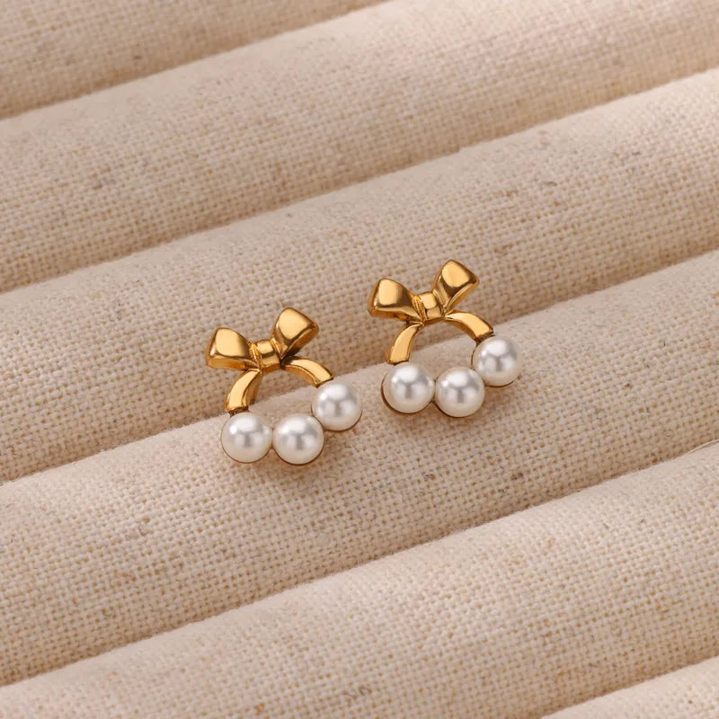 G10 - Aretes moños con perlitas. Color dorado. Acero inoxidable.