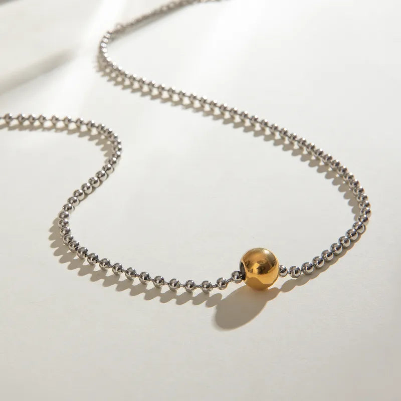 J23 - Collar de bolitas con dije esfera. Color plateado con dorado. Acero inoxidable.