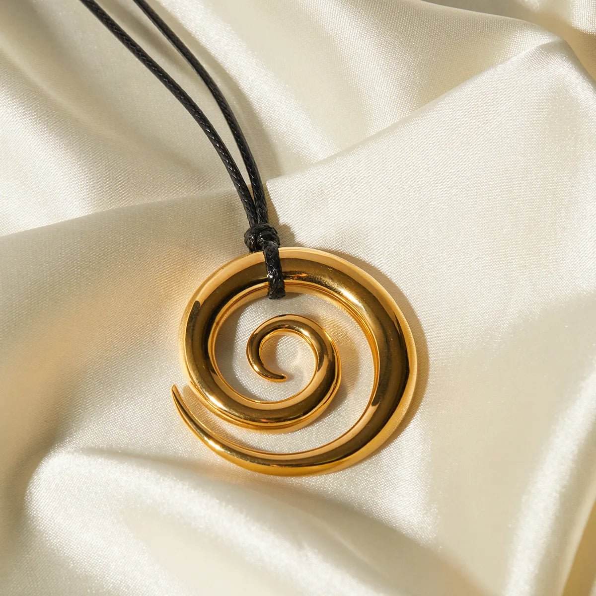 Collar de cuero negro con dije grande en forma de espiral. Color dorado. Acero inoxidable.