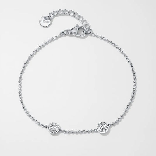 K23 - Pulsera delgada con dos dijes redondos con circonias. Color plateado. Acero inoxidable.