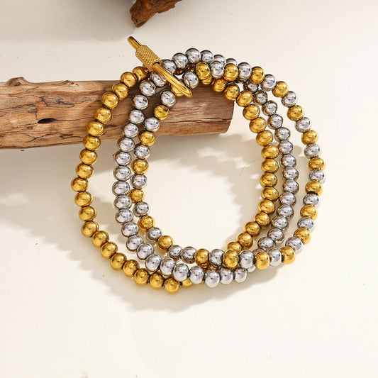 Pulsera triple con broche ovalado. Color dorado y plateado. Acero inoxidable.