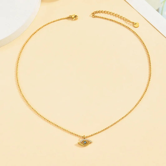 Collar con dije chico de ojo turco con circonias y circonia celeste en el centro. Color dorado. Acero inoxidable.