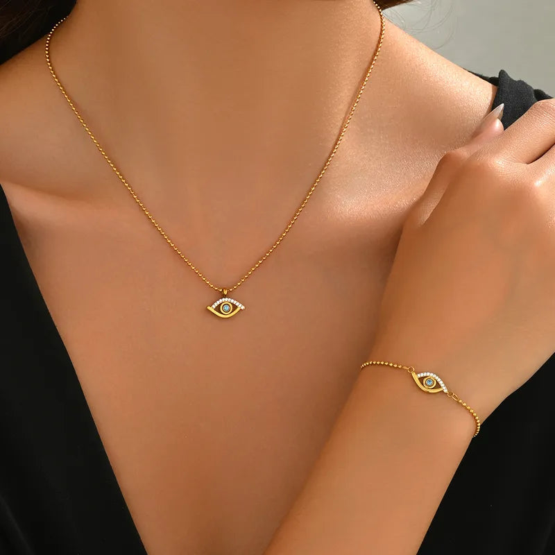 Collar con dije chico de ojo turco con circonias y circonia celeste en el centro. Color dorado. Acero inoxidable.