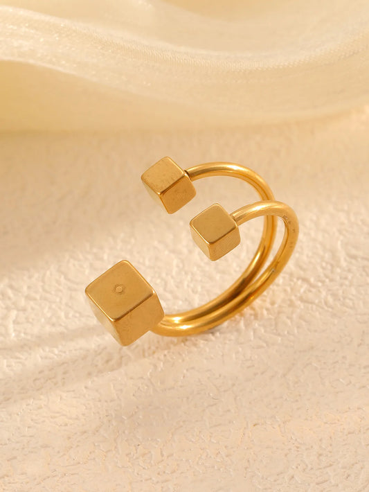 Anillo con 3 cubos, ajustable. Color dorado. Acero inoxidable.
