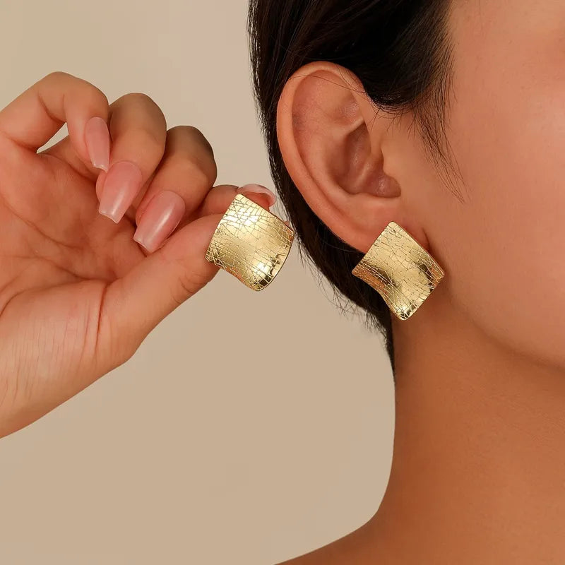 Aretes de rombos con textura. Color dorado claro. Bisutería.