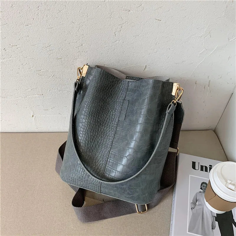 Bolsa tamaño mediana. Color gris azulado con efecto cocodrilo. Incluye correa para colgar cruzada.