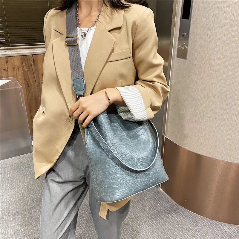Bolsa tamaño mediana. Color gris azulado con efecto cocodrilo. Incluye correa para colgar cruzada.