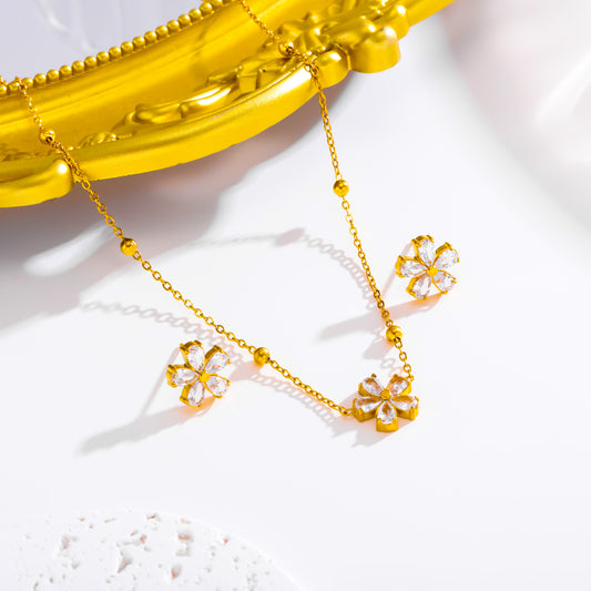 Juego aretes y collar flores de cristales. Color dorado. Acero inoxidable.