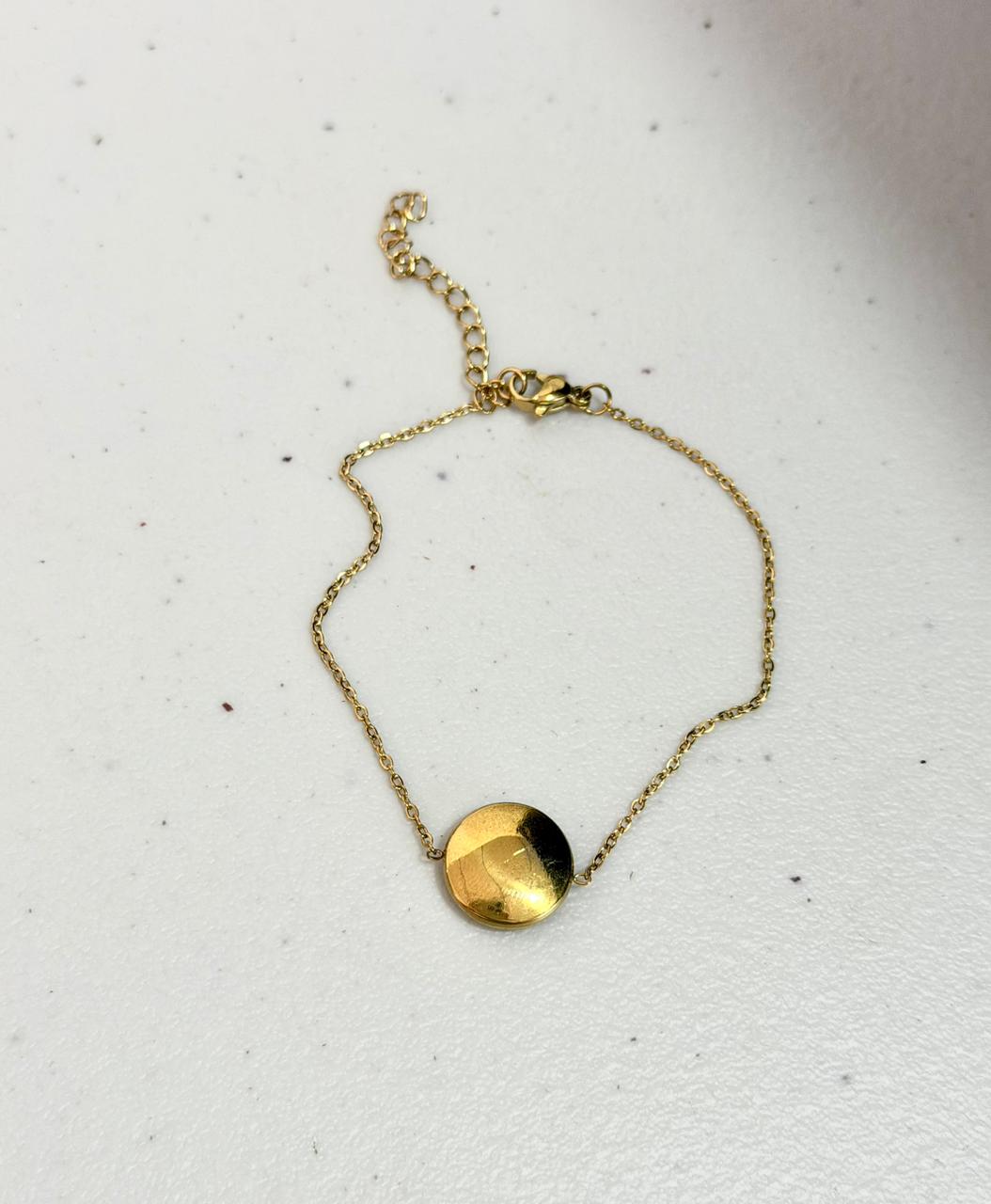 F24 - Pulsera con dije redondo. Color dorado. Acero inoxidable.