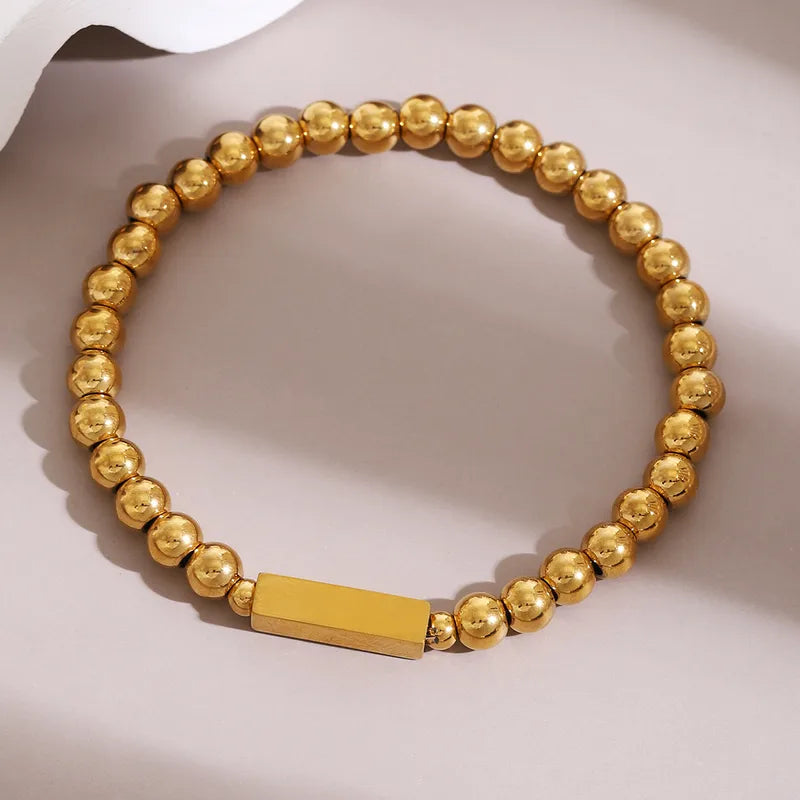 Pulsera bolitas con dije rectangular. Color dorado. Acero inoxidable.