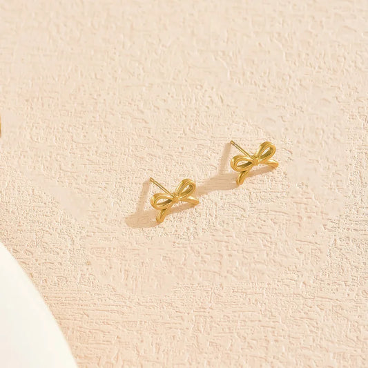 H19 - Aretes chicos forma de moñito. Color dorado. Acero inoxidable.