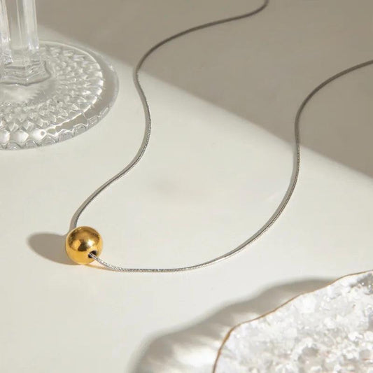 H20 - Collar con dije de esfera. Color plateado con dorado. Acero inoxidable.