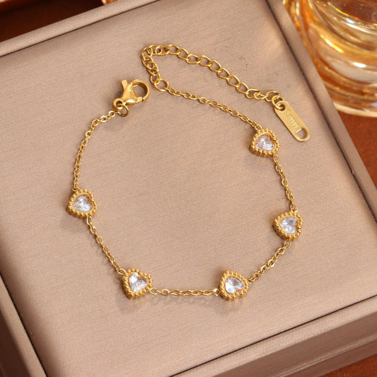 J21 - Pulsera con corazones de circonias. Color dorado. Acero inoxidable.